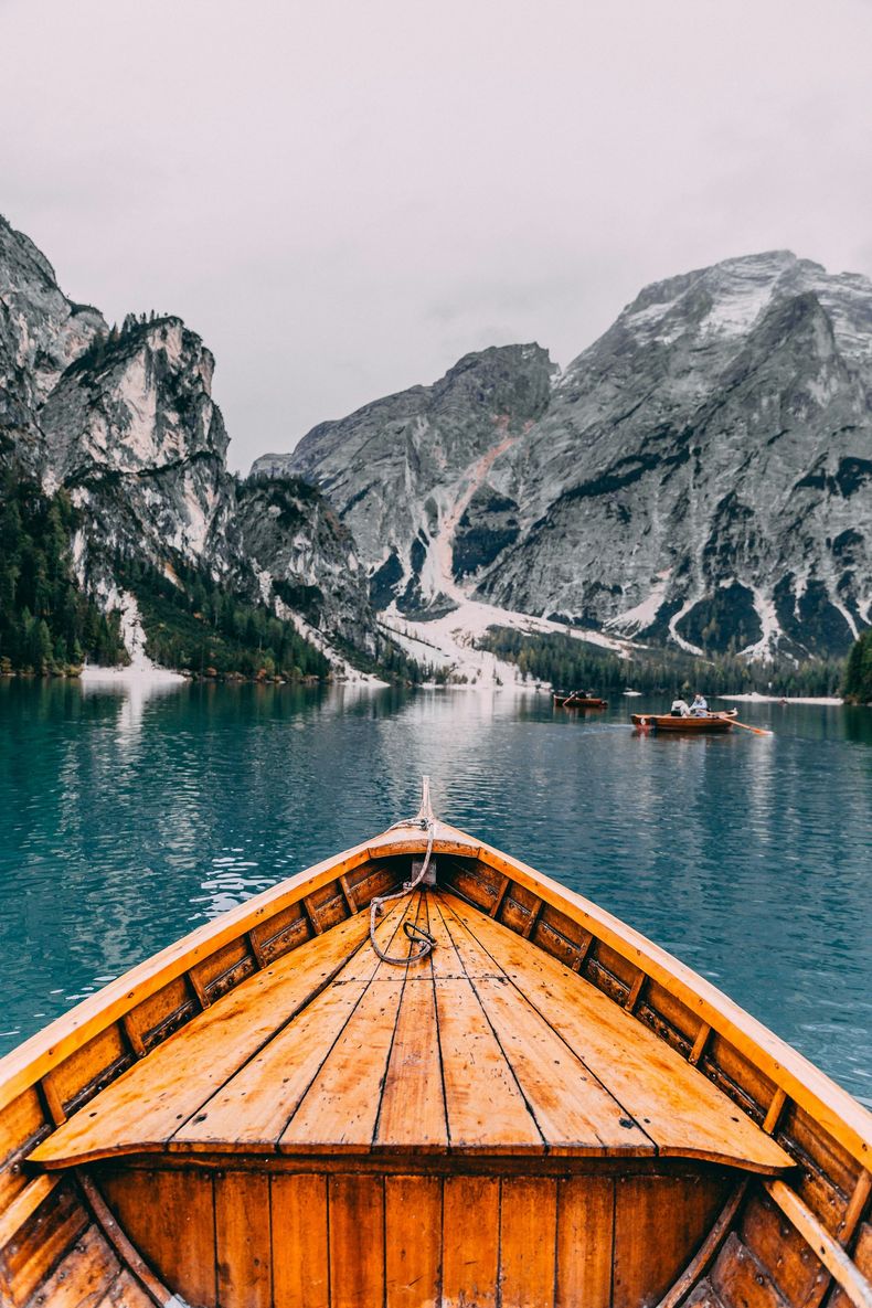 A wooden boat is floating on a lake with mountains in the background.