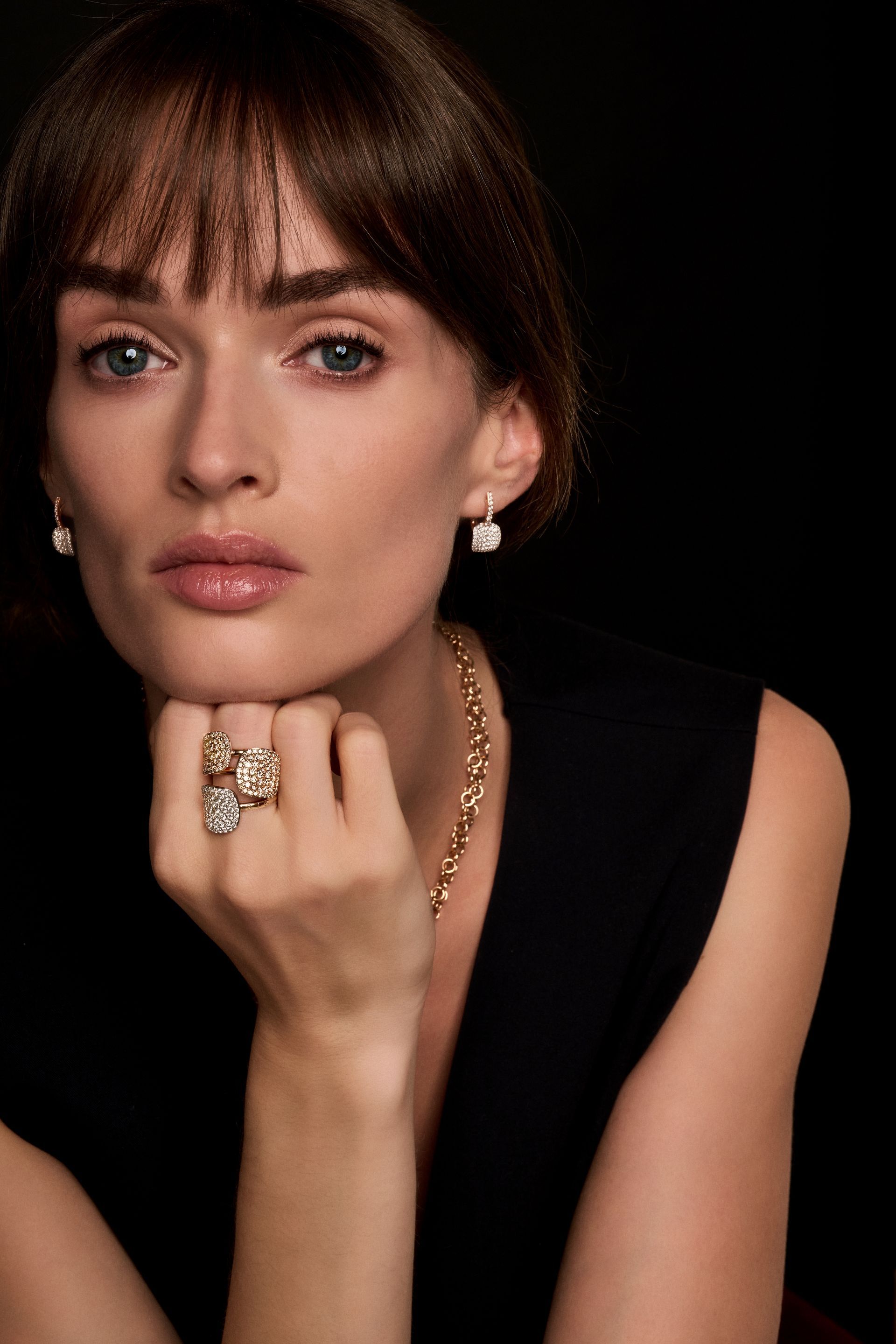 Frau mit Billie Schmuck, posierend, schwarzes Oberteil, dunkler Hintergrund.