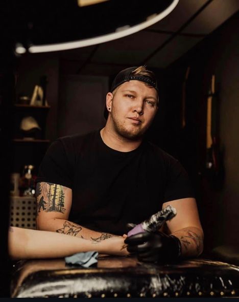 A man is getting a tattoo on a woman 's arm.