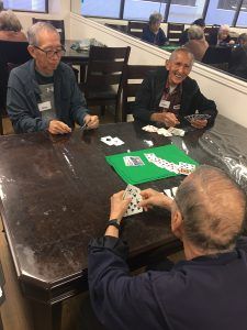 A group of older men are sitting at a table playing cards.