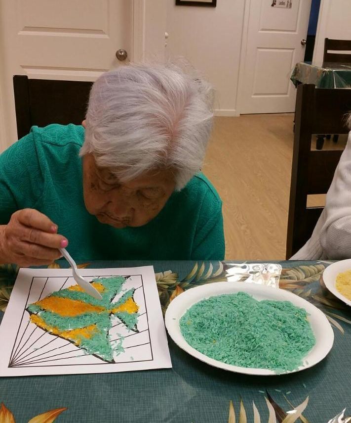 A woman sitting at a table with a plate of green rice