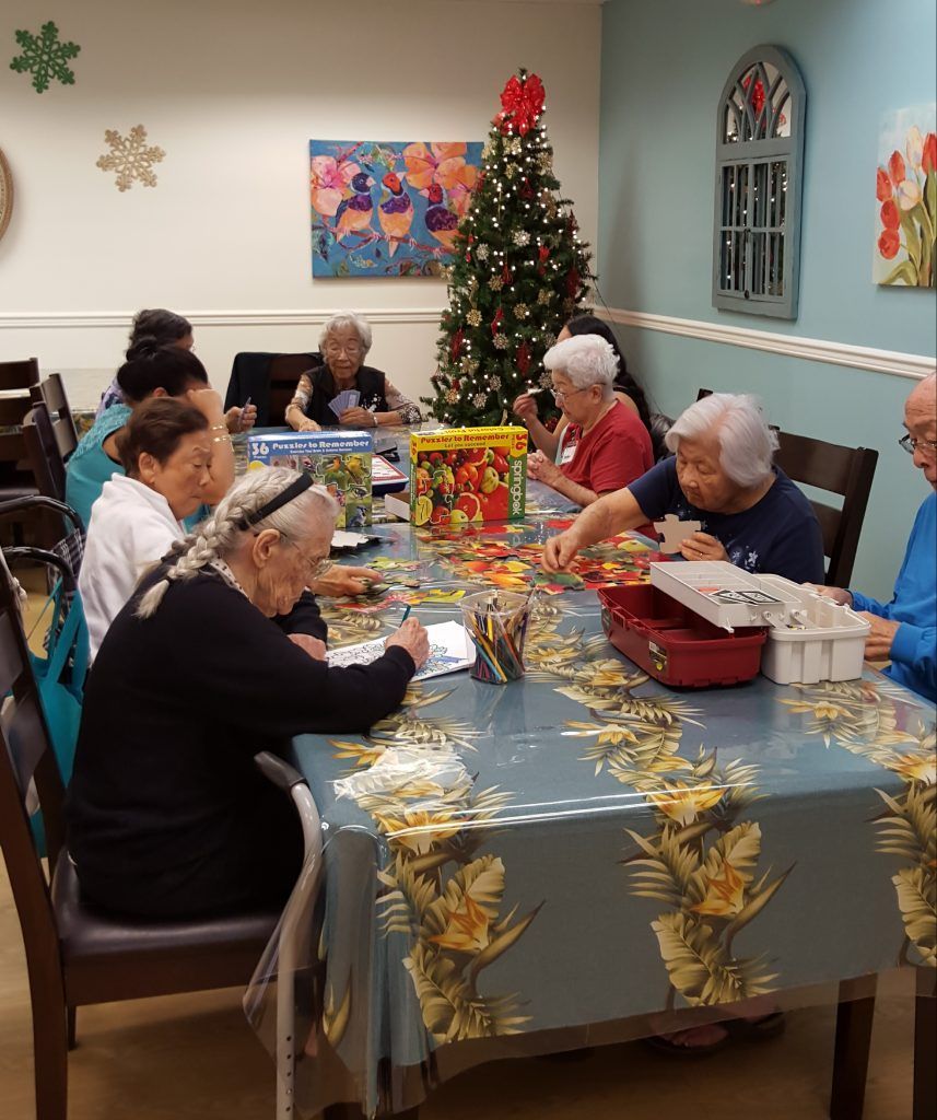 A group of people are sitting around a table with a christmas tree in the background