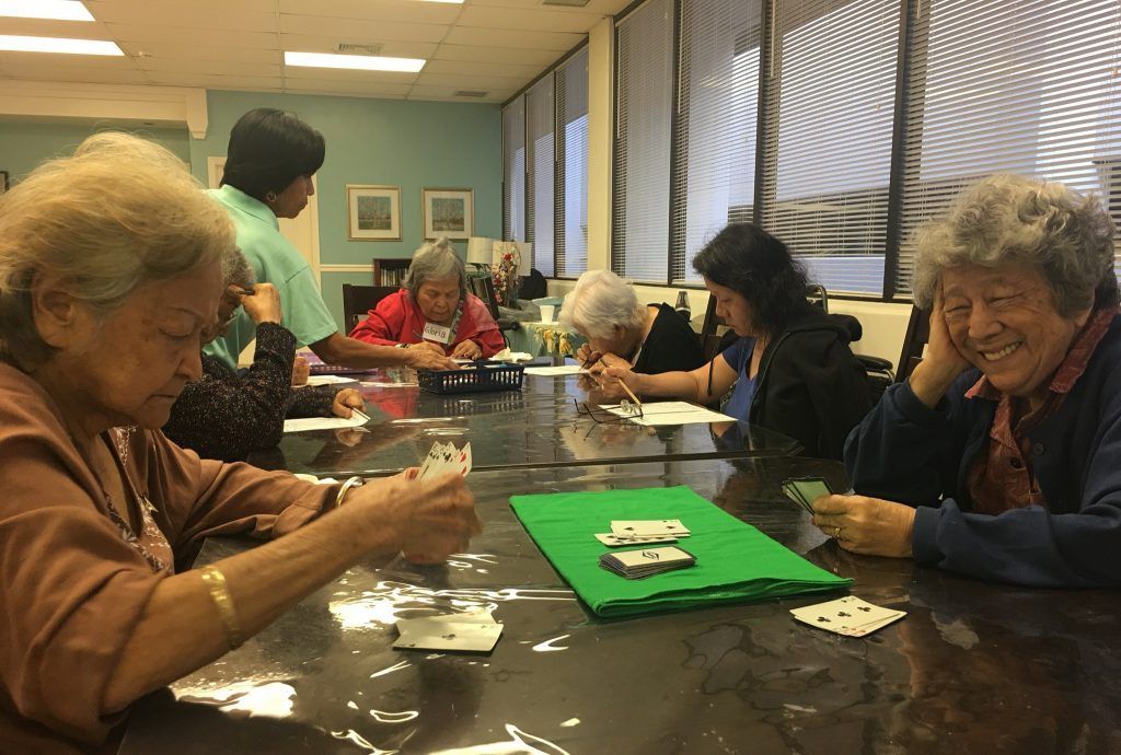 A group of elderly women are sitting at a table playing cards.