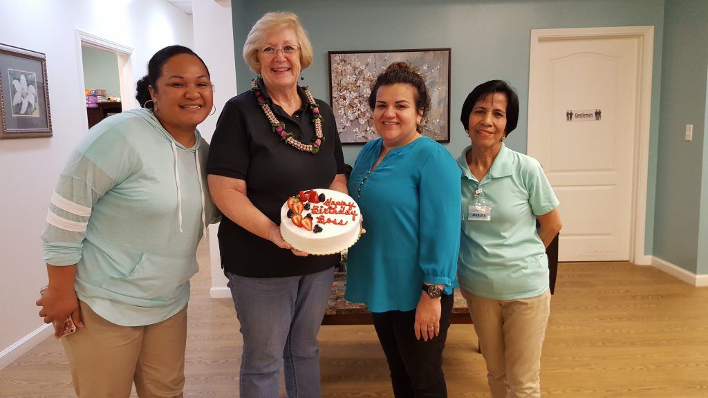 A group of women are standing next to each other holding a cake.