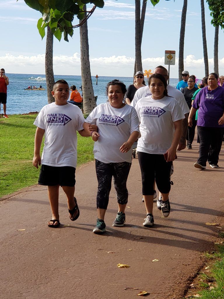 A group of people are walking down a path near the ocean.