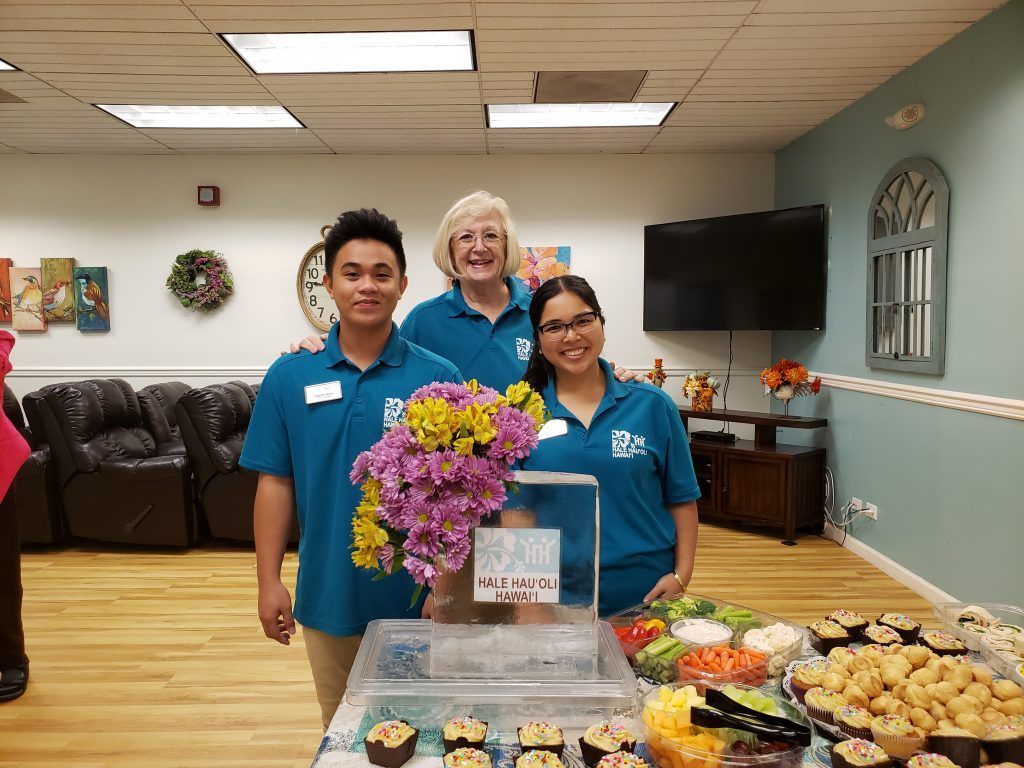A group of people are posing for a picture in front of a table with food.