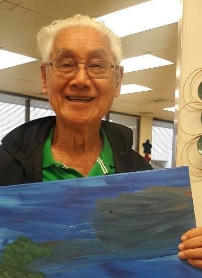 A man in a green shirt is holding a painting