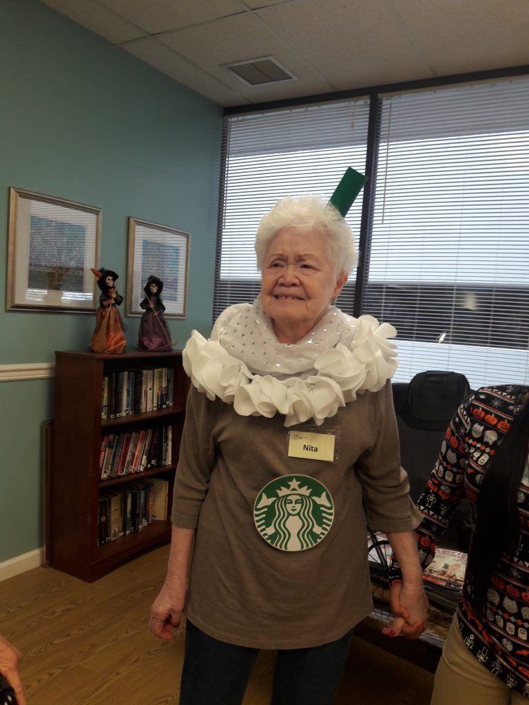 A woman in a starbucks costume is standing in a room