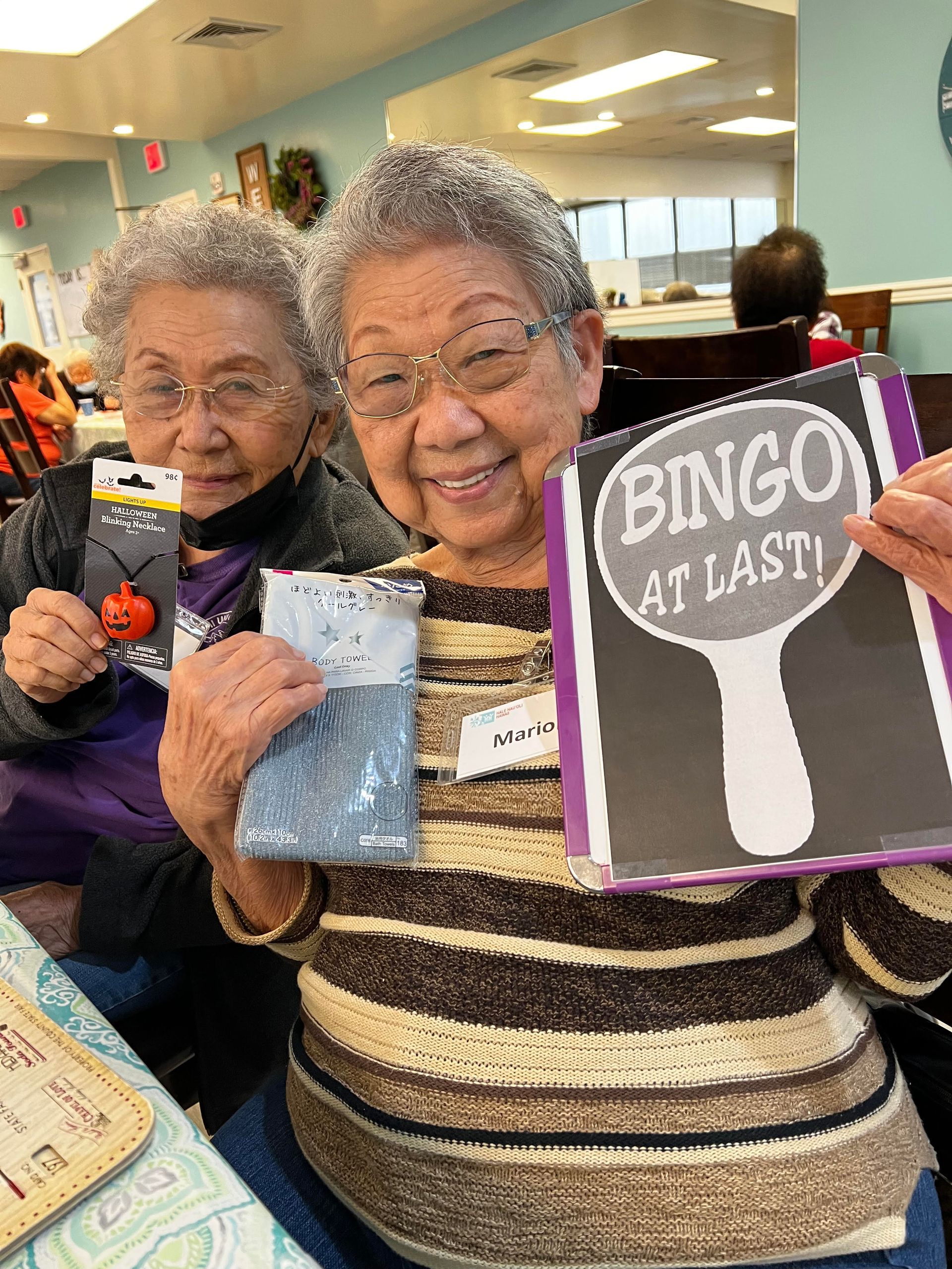 Two elderly women are holding a sign that says bingo at last.
