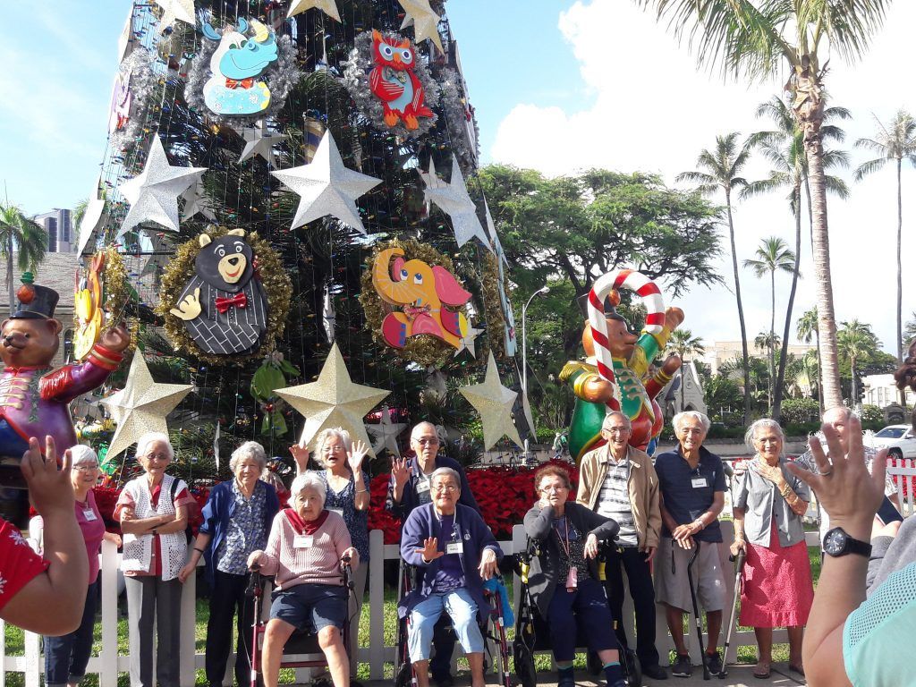 A group of people are standing in front of a christmas tree.