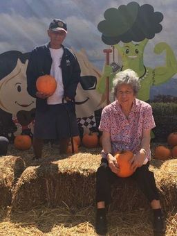A man and a woman are holding pumpkins in a pumpkin patch
