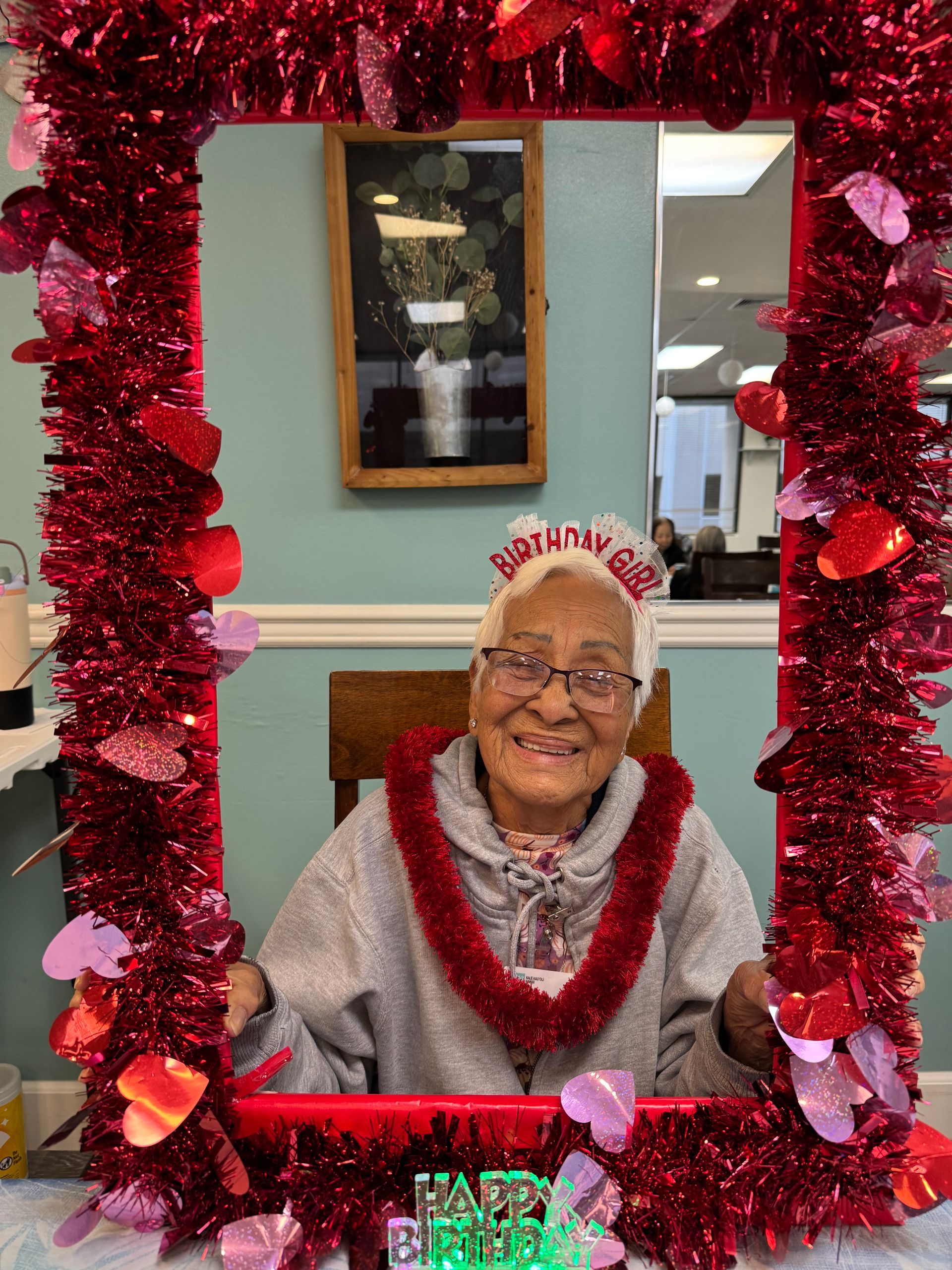 An elderly woman is posing for a picture in a frame decorated for valentine 's day