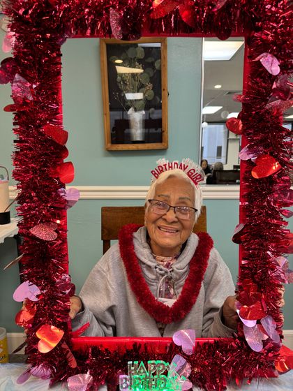 An elderly woman is posing for a picture in a frame decorated for valentine 's day
