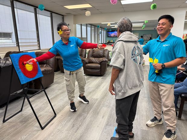A group of people are playing a game of archery in a living room.