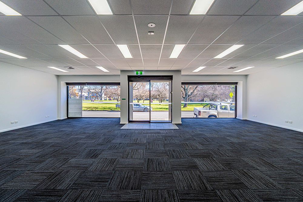 A Large Empty Room with A Black Carpet and A Sliding Glass Door — Construction & Renovation Services in Dubbo, NSW