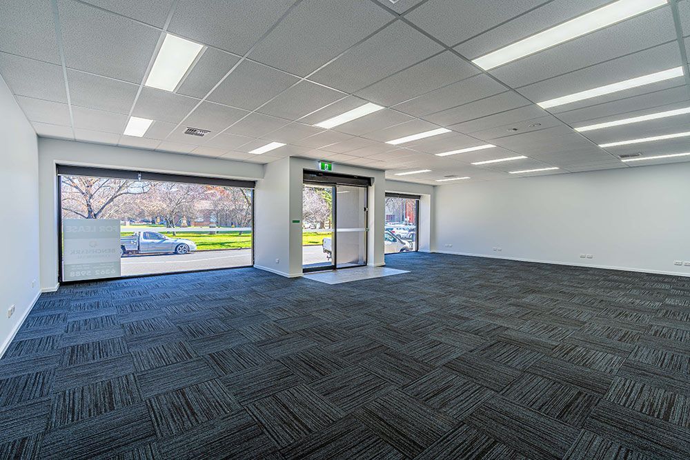 A Large Empty Room with A Carpeted Floor and A Sliding Glass Door — Construction & Renovation Services in Dubbo, NSW