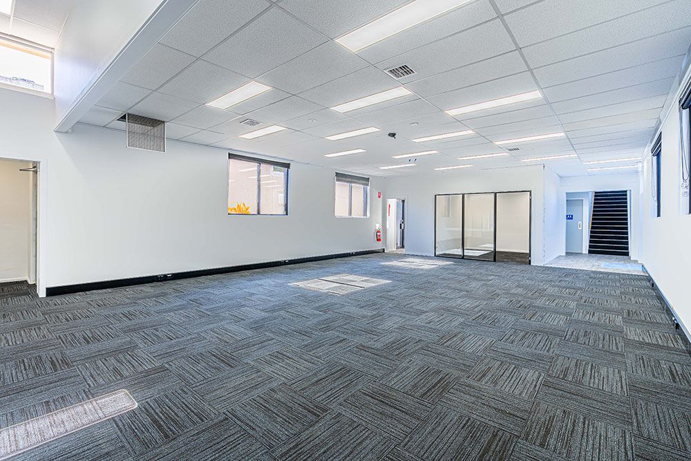 A Spacious, Empty Room Featuring White Walls and A Carpeted Floor — Construction & Renovation Services in Dubbo, NSW