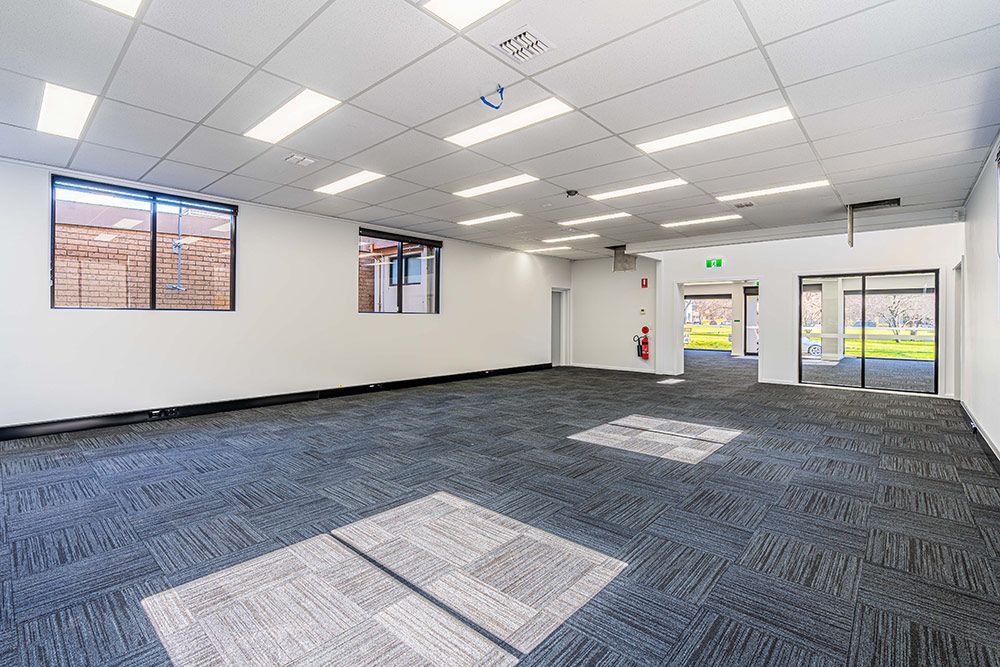 A Large Empty Room with A Carpeted Floor and White Walls — Construction & Renovation Services in Dubbo, NSW