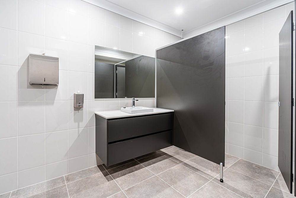 A Bathroom with A Sink, Mirror, and Toilet Paper Dispenser — Construction & Renovation Services in Dubbo, NSW