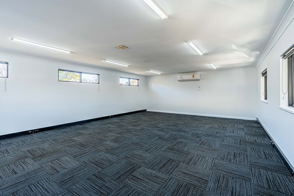 A Huge Empty Room with White Walls and A Carpet — Construction & Renovation Services in Dubbo, NSW