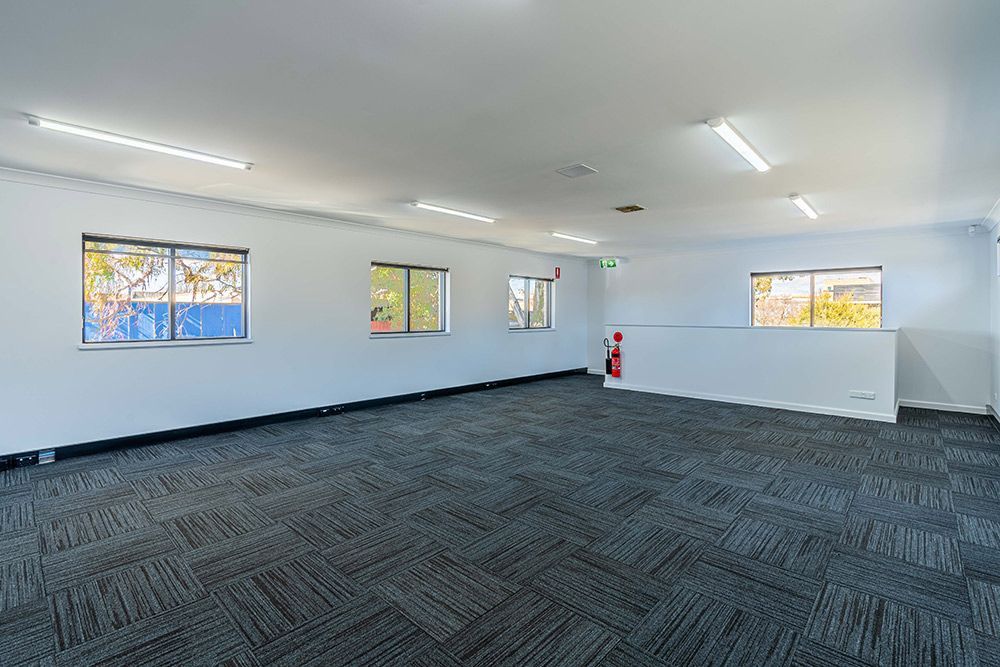 A Large Empty Room with A Carpeted Floor and Windows — Construction & Renovation Services in Dubbo, NSW