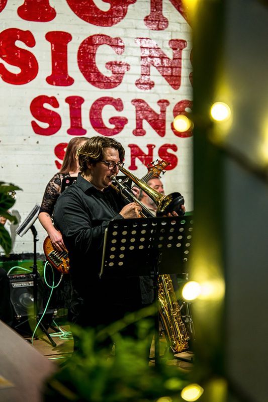 A Group of People Are Playing Instruments in Front of A Sign that Says Sign Signs — Construction & Renovation Services in Dubbo, NSW