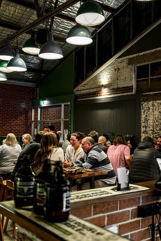 A Group of People Are Sitting at Tables in A Restaurant — Construction & Renovation Services in Dubbo, NSW