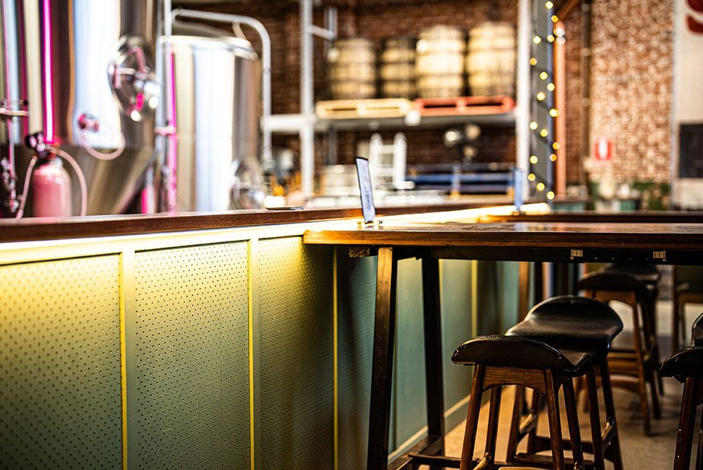 A Bar with Stools and A Table in A Brewery — Construction & Renovation Services in Dubbo, NSW