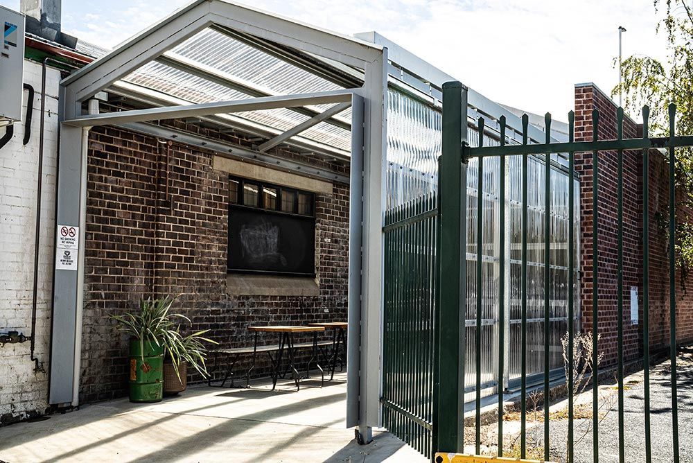 A Brick Building with A Green Fence and A Canopy Over It — Construction & Renovation Services in Dubbo, NSW