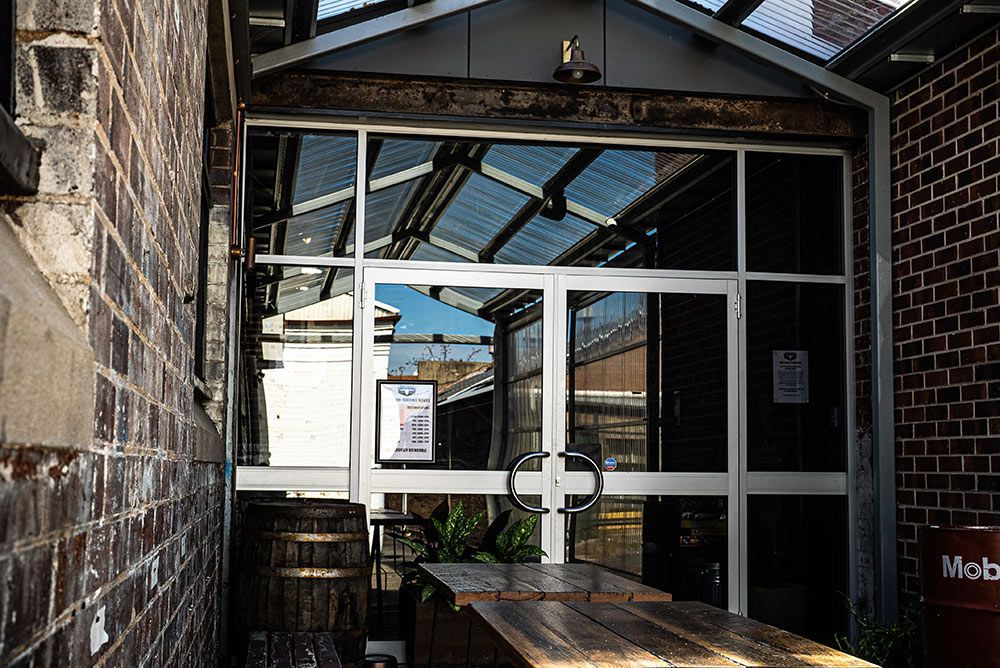 A Brick Building with A Glass Door and A Table in Front of It — Construction & Renovation Services in Dubbo, NSW