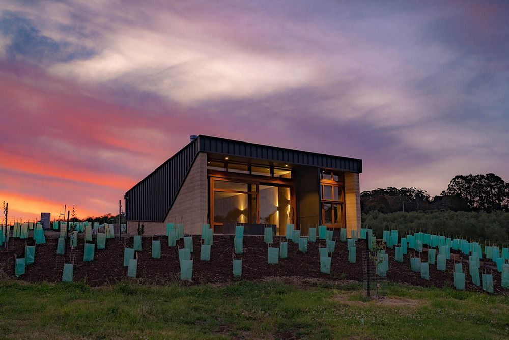 A House Is Sitting in The Middle of A Field with A Sunset in The Background — Construction & Renovation Services in Dubbo, NSW