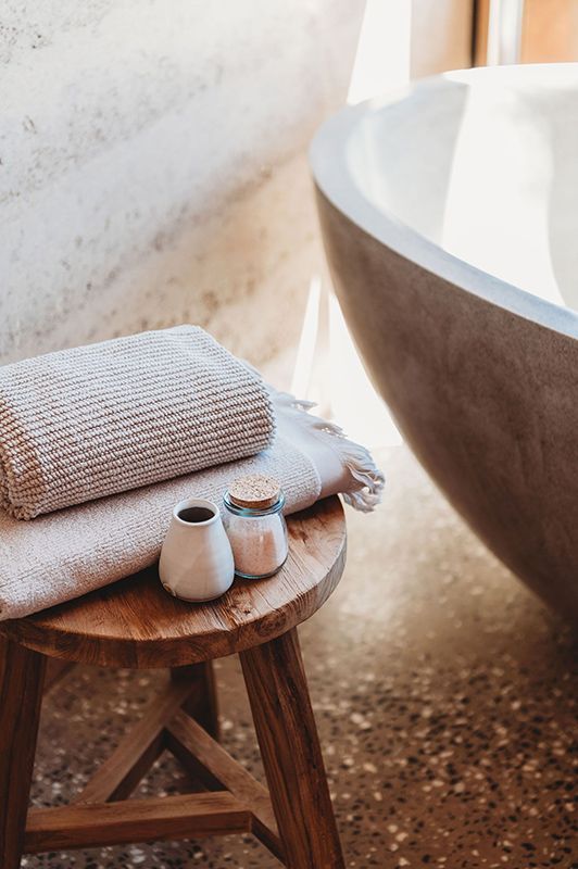 A Wooden Stool with Towels and Candles on It in A Bathroom Next to A Bathtub — Construction & Renovation Services in Dubbo, NSW