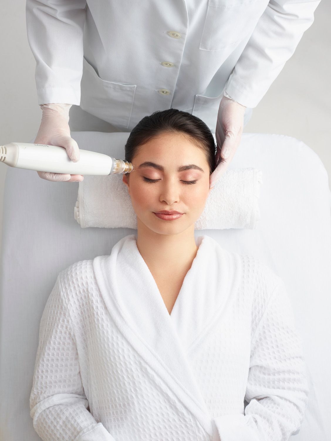 A woman is laying on a bed getting a facial treatment.