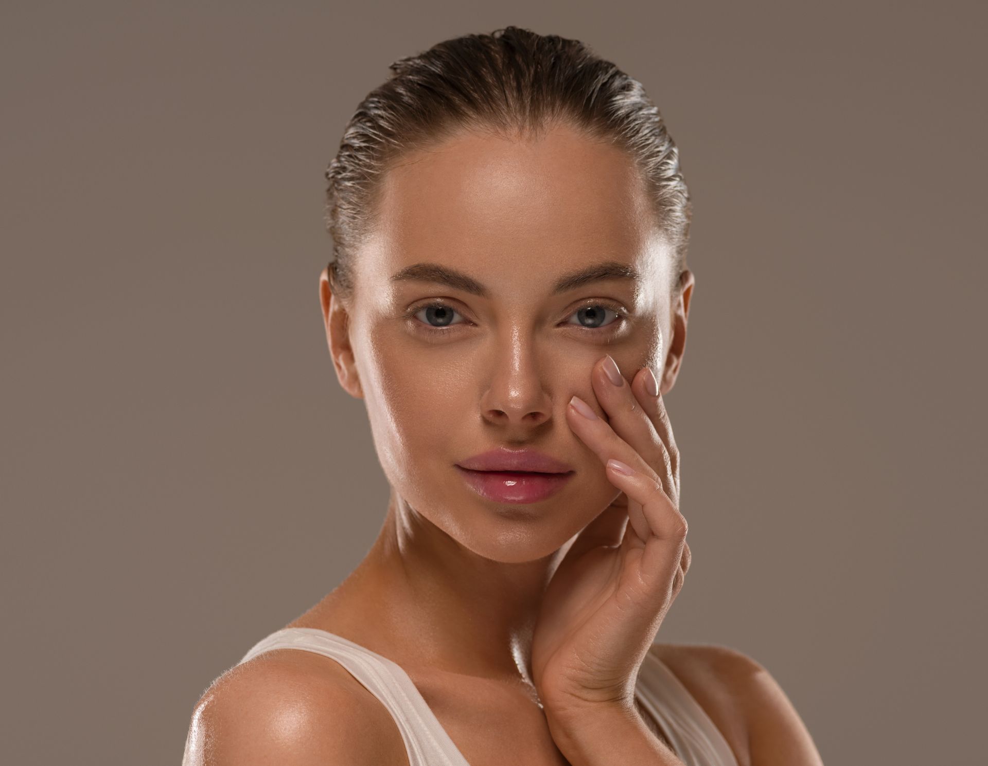 A woman is touching her face with her hand and looking at the camera.