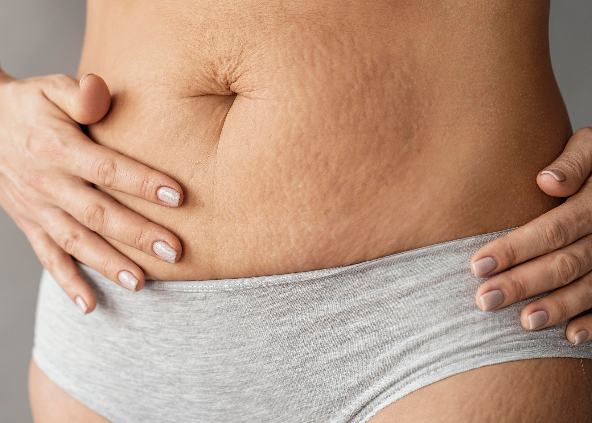 A woman is holding her stomach with her hands.