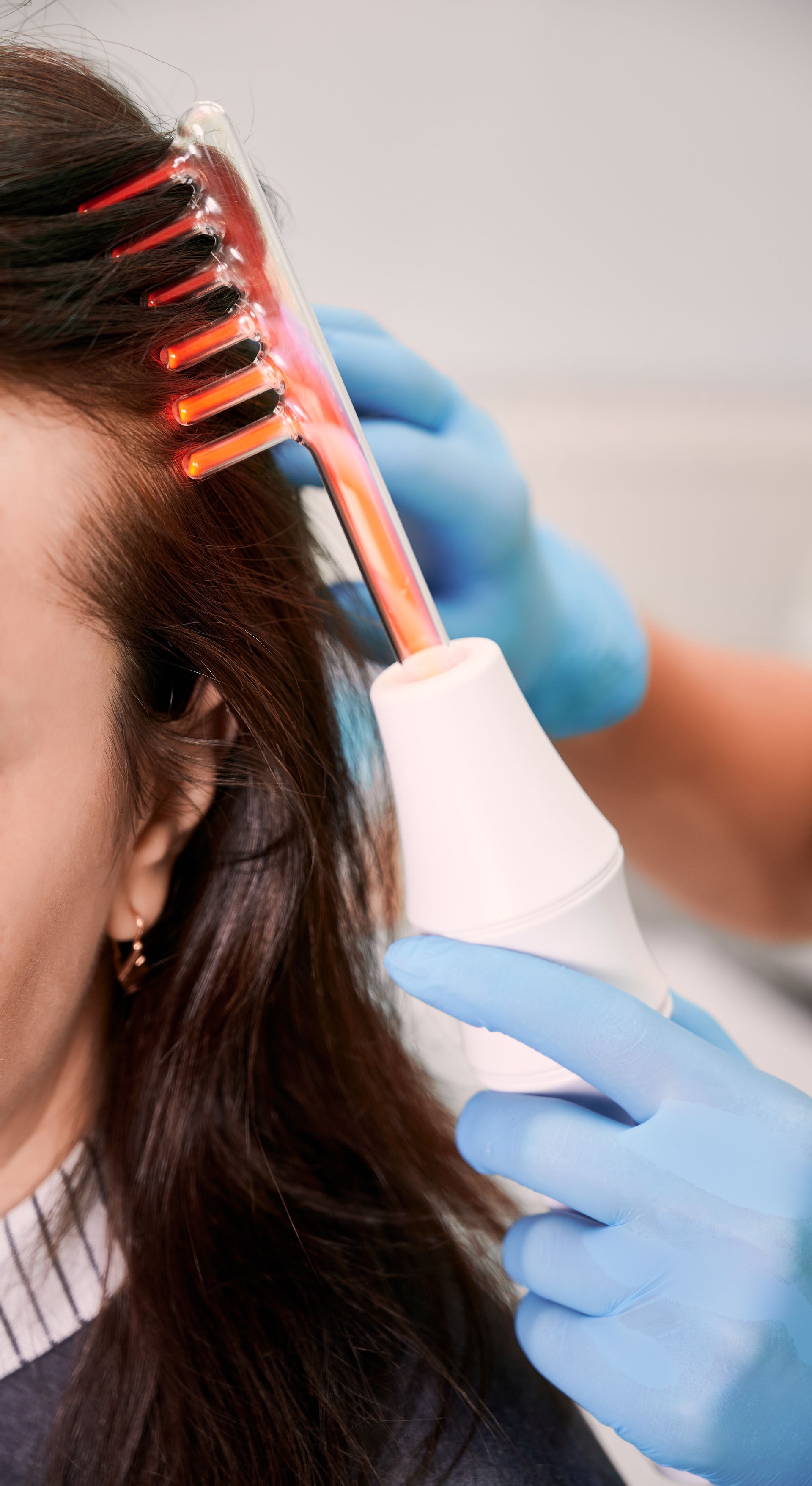 A woman is getting a hair treatment with a comb.