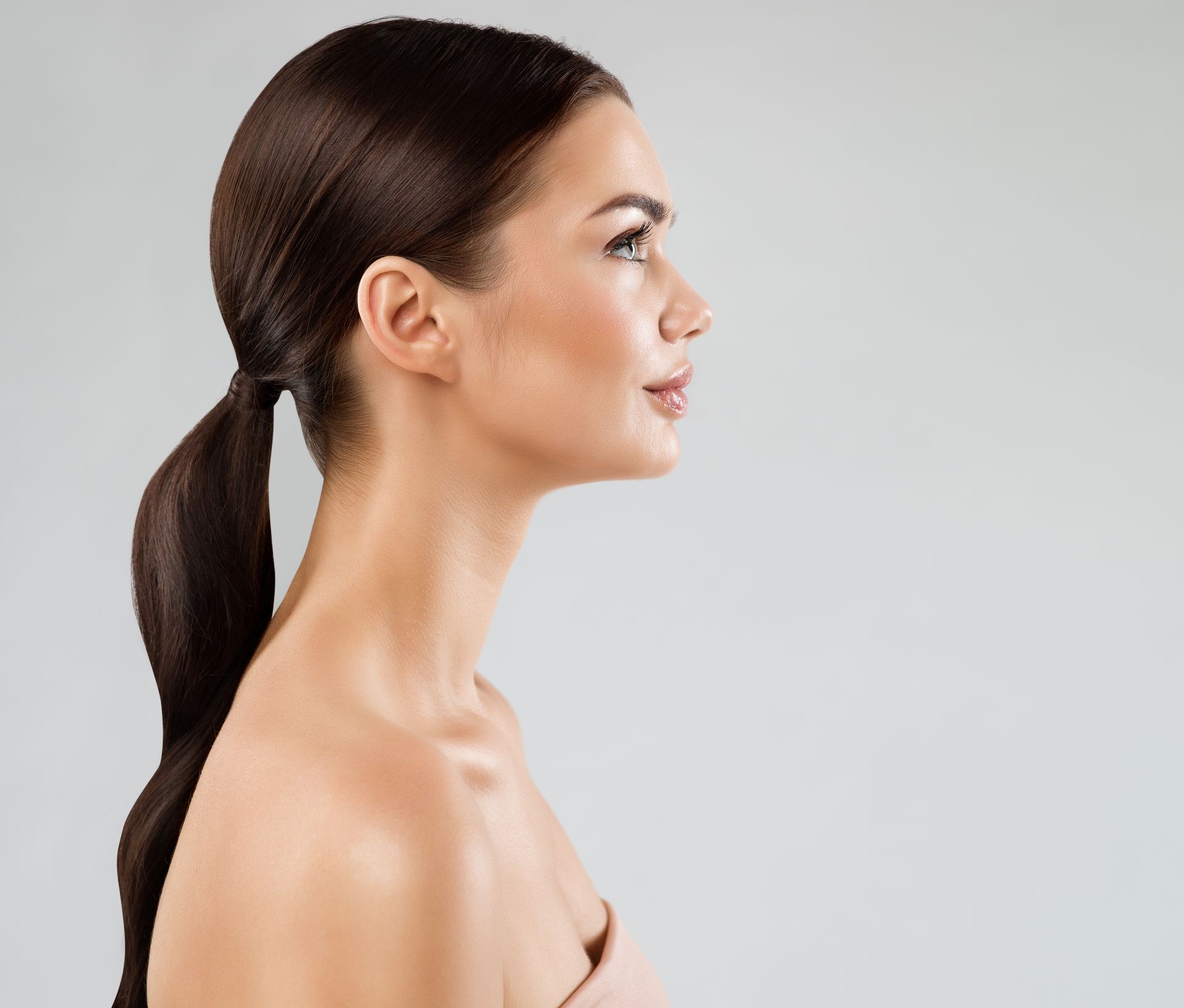 A woman with long hair in a ponytail is looking to the side.