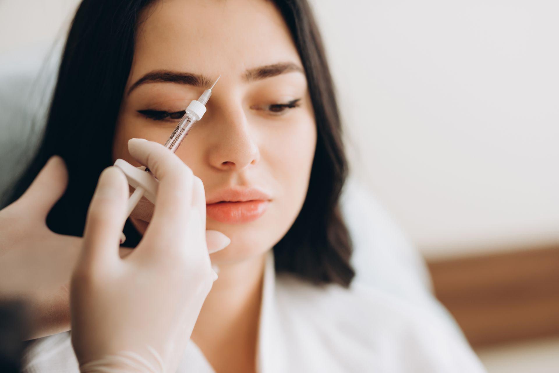 A woman is getting a botox injection in her face.