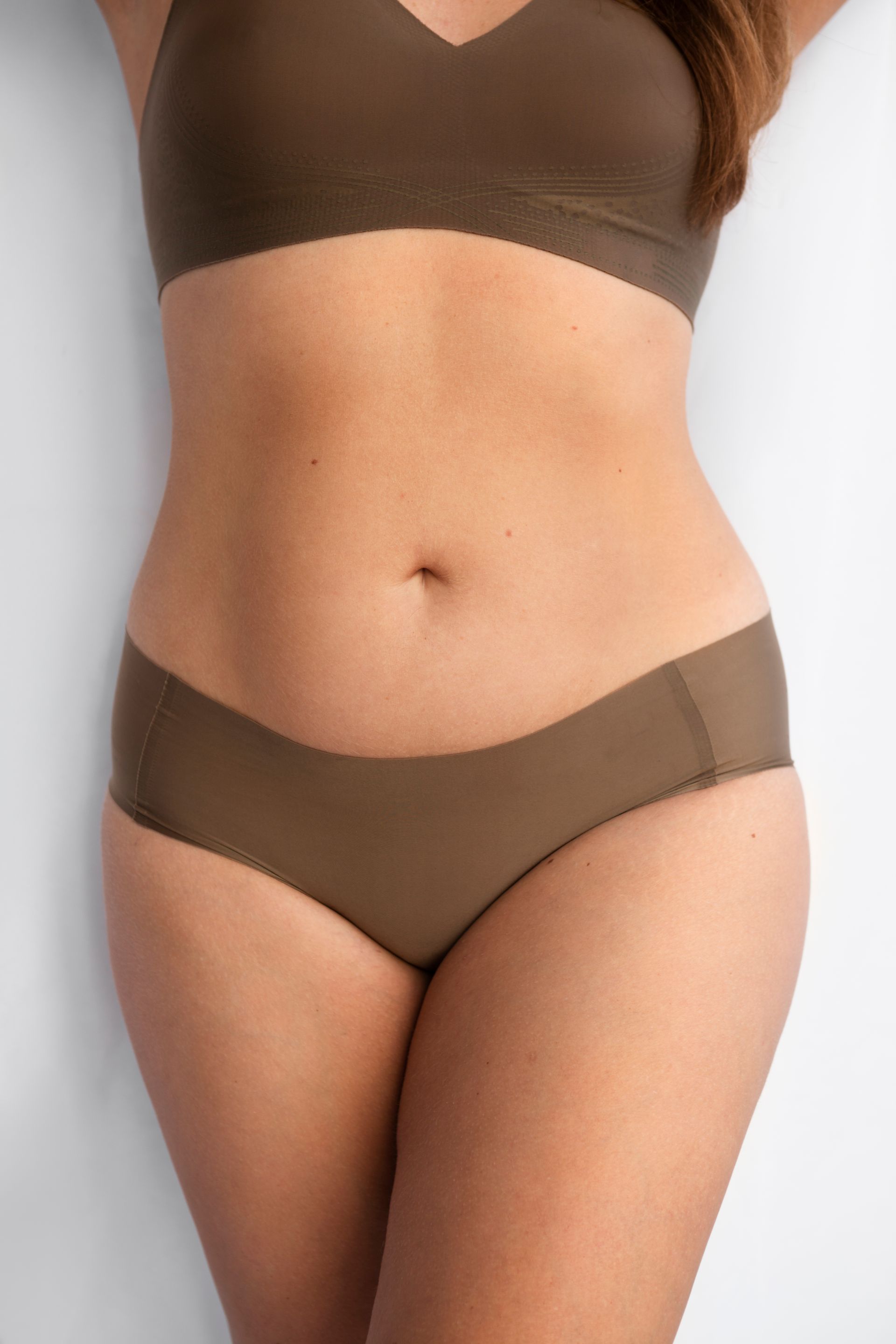 A woman is wearing a brown bra and brown underwear.