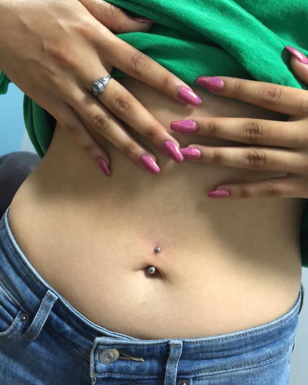 A woman with pink nails has a belly button piercing