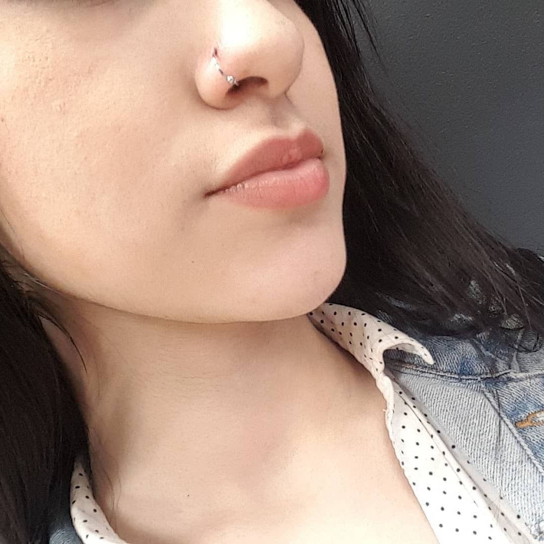 A close up of a woman 's face with a nose ring.