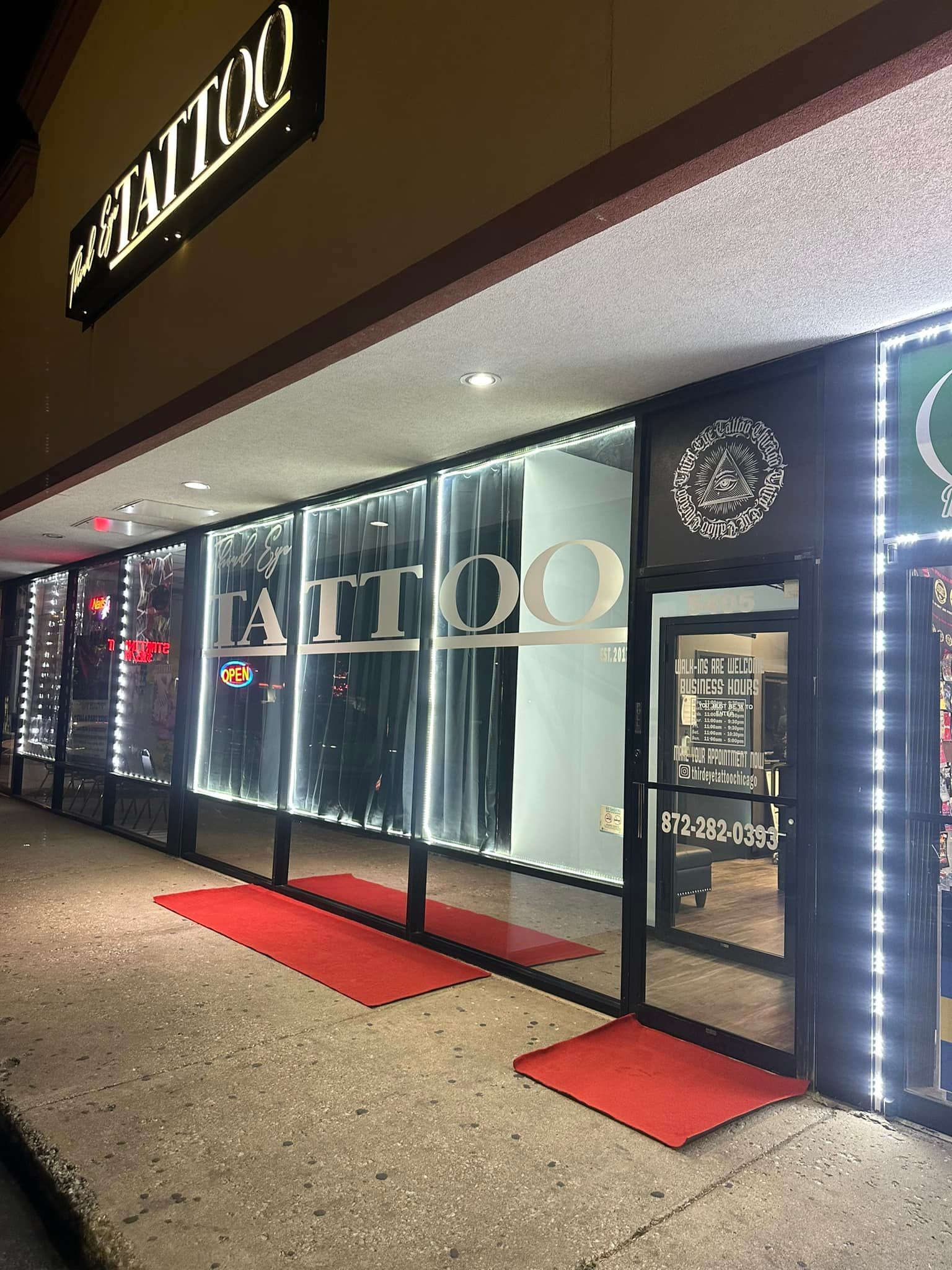 A tattoo shop with a red rug in front of it.