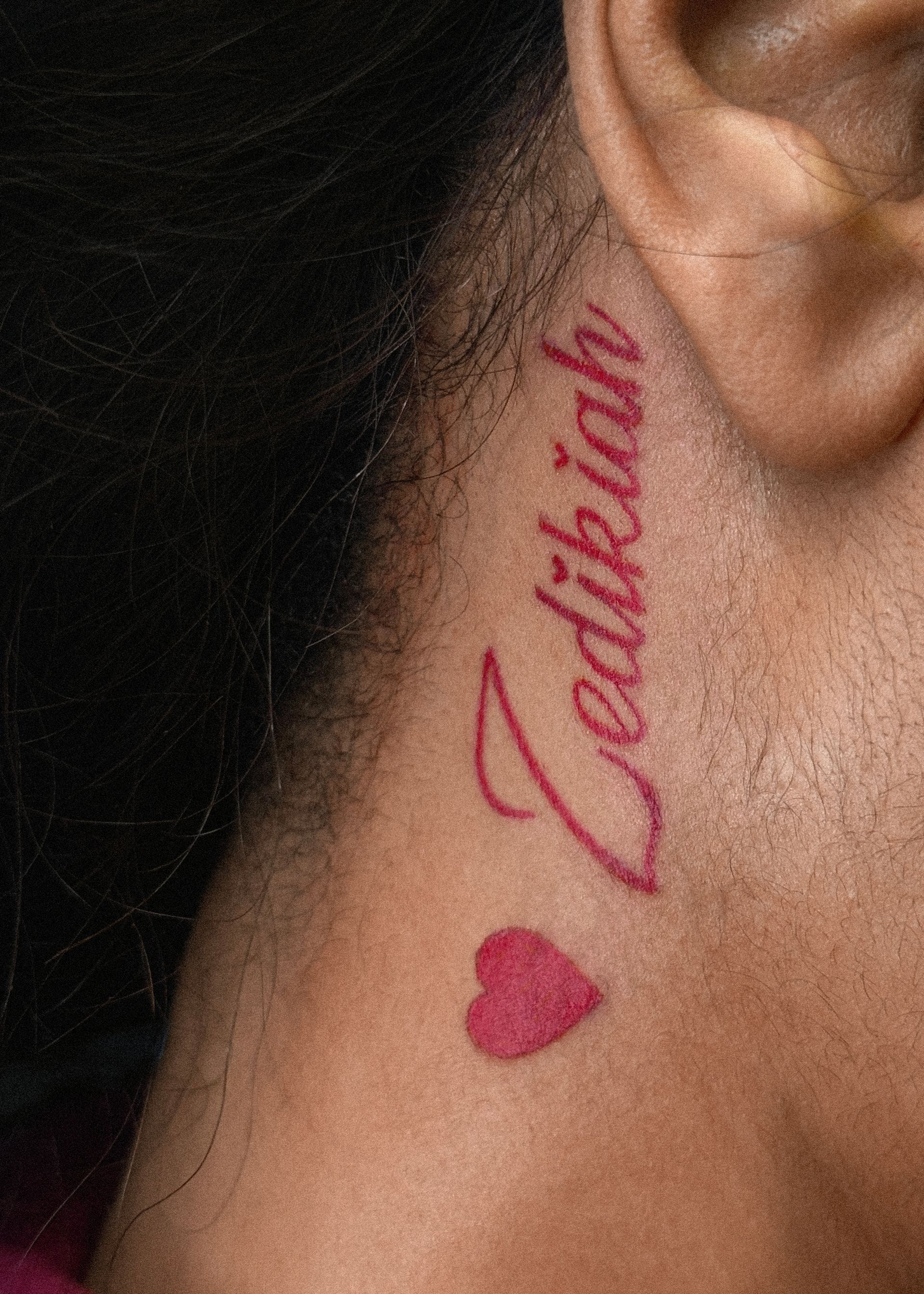 Neck tattoo: red script name 