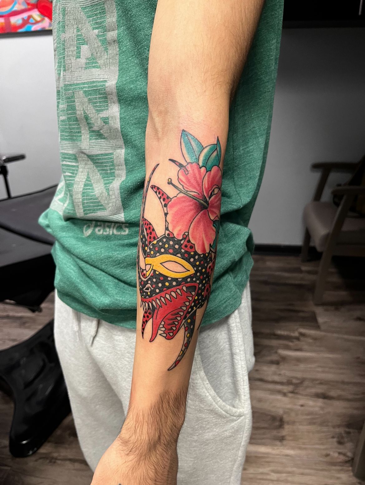 Arm tattoo of a red and black floral design with a pink hibiscus flower.