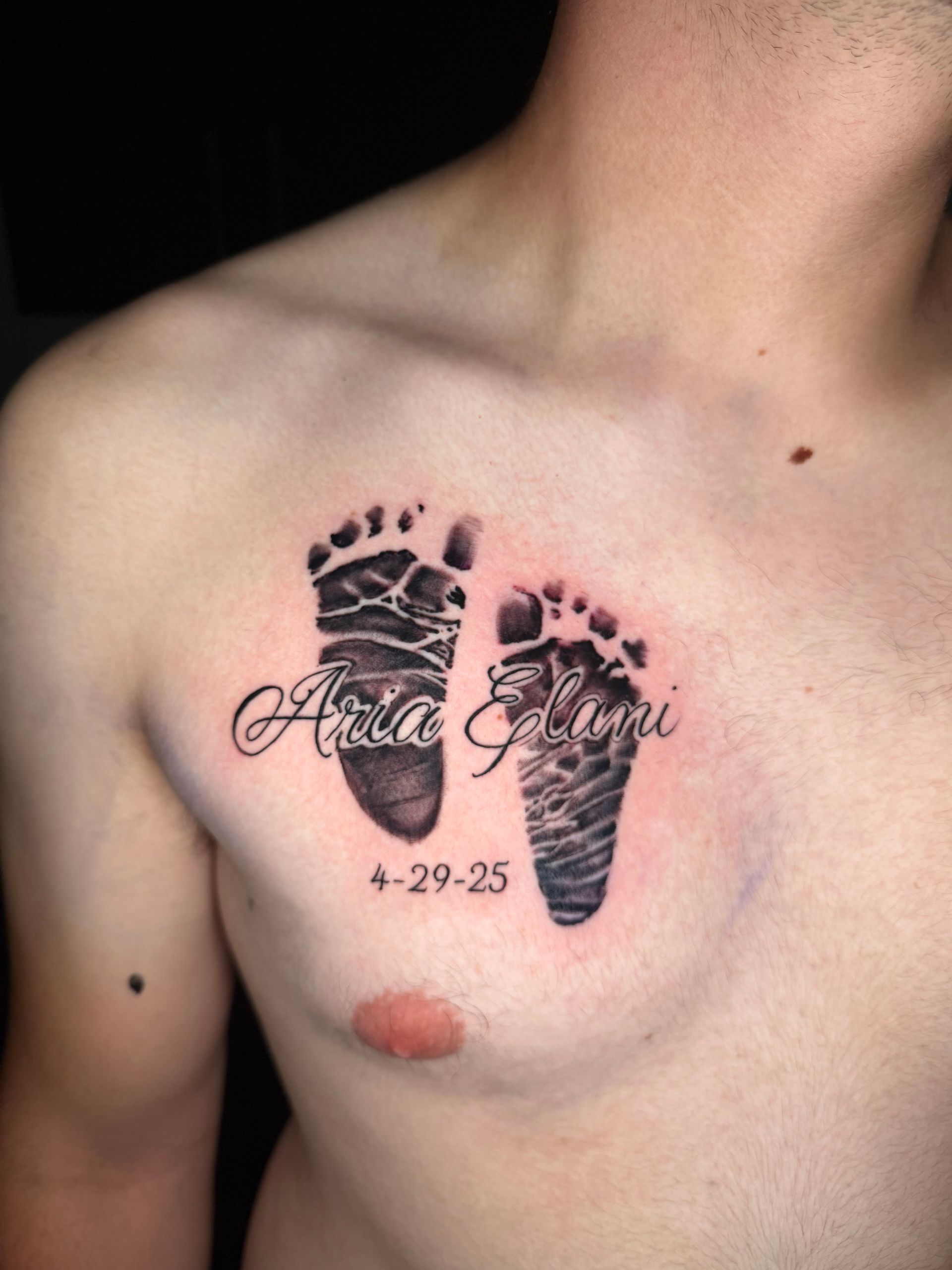 Tattoo on chest: baby footprints with the name