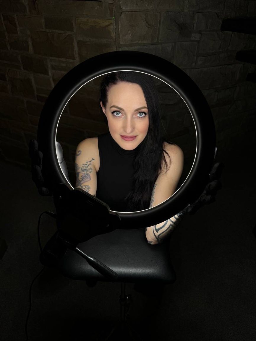 A woman is sitting in front of a ring light