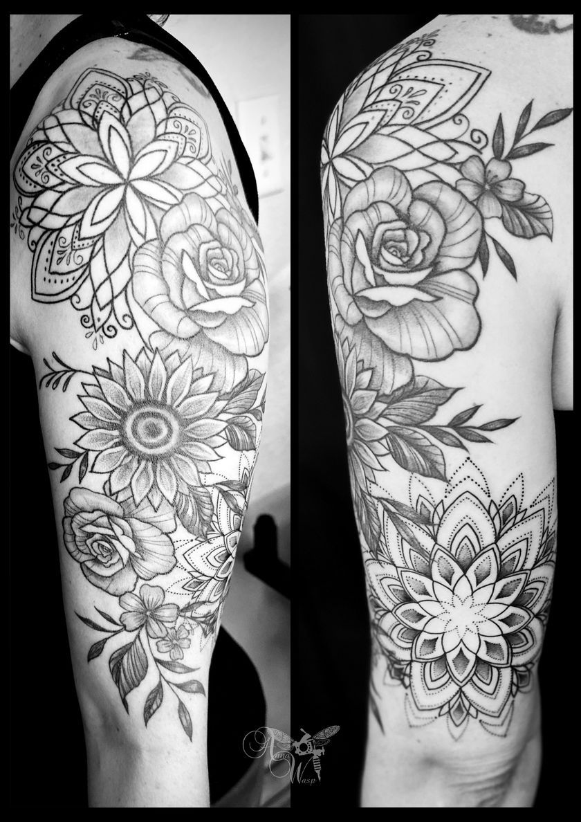 A black and white photo of a tattoo of flowers on a woman 's arm.