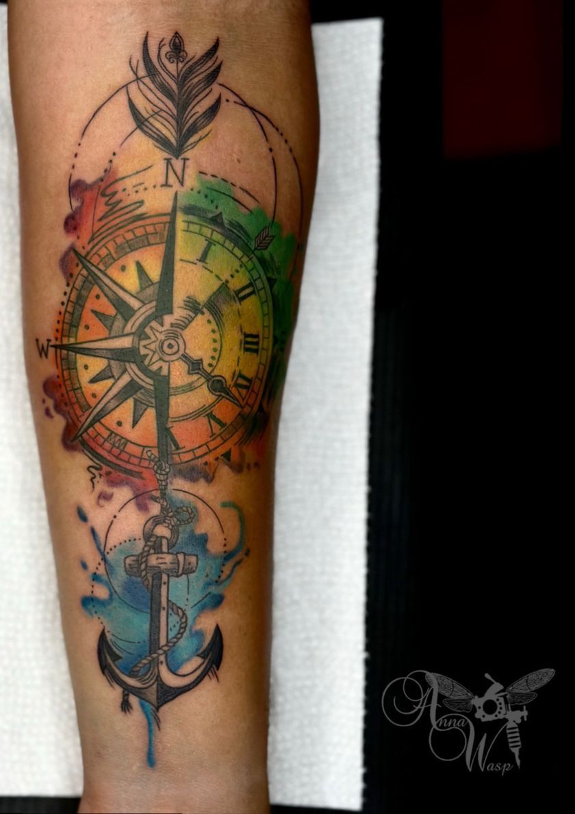 A tattoo of a compass anchor and arrow on a person 's arm