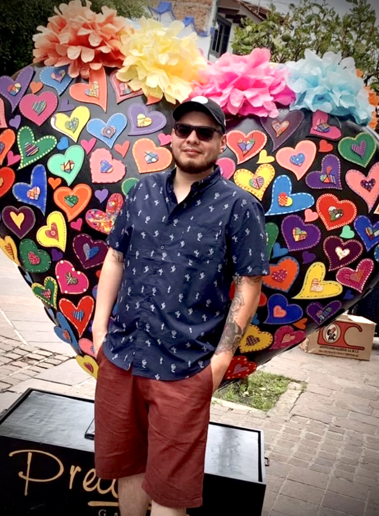 A man is standing in front of a colorful heart shaped sculpture
