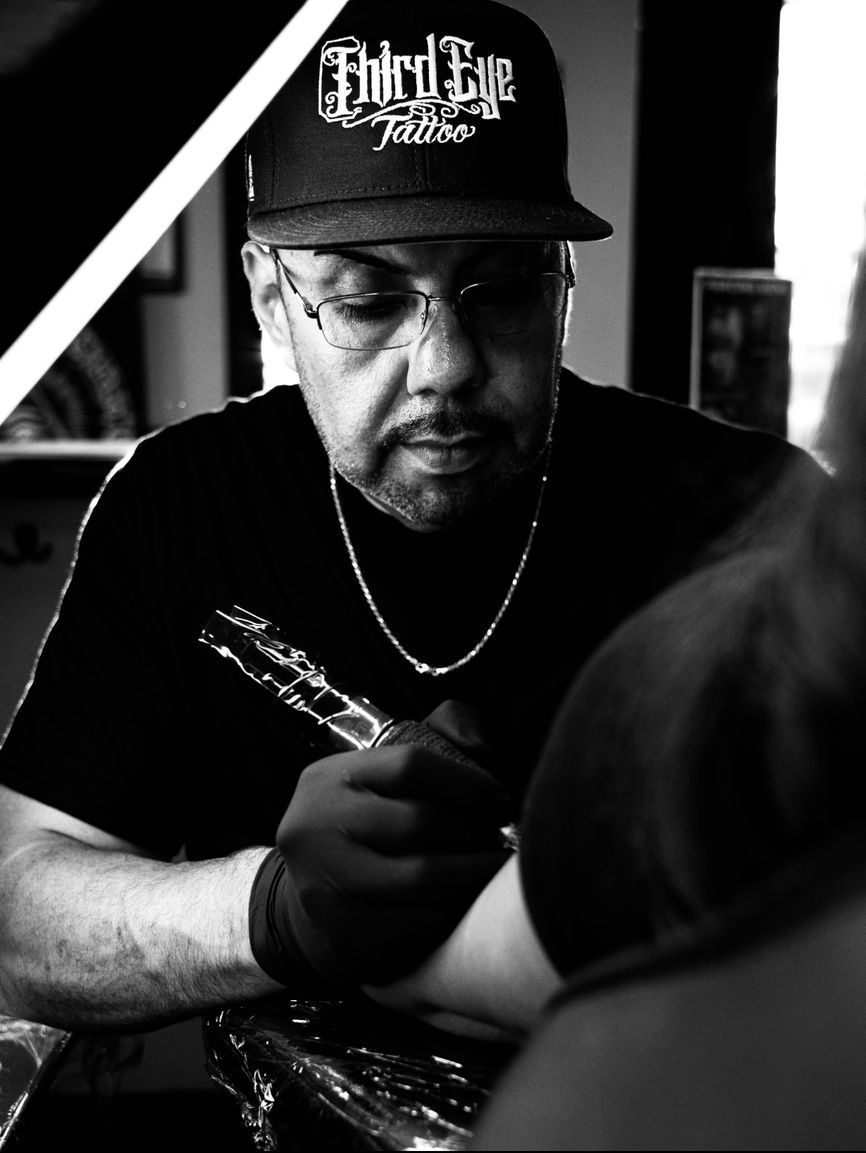 A man is getting a tattoo on another man 's arm.